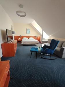 a hotel room with a bed and a blue chair at Hotel Daria in Tychy +70 photos