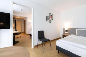 a bedroom with a bed and a chair and a table at Brera Stuttgart in Stuttgart