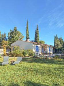 two white chairs in the grass in front of a house at Vintage Provence in Arles