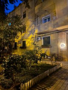 a yellow building with a tree in front of it at Mullaga Premium Stays in Tirana