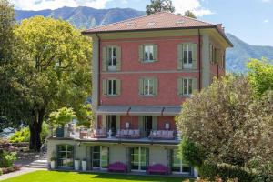 a large red building with chairs on the balcony at Villa Artemisia by MyVillaCollection in Lenno