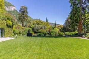 a large green lawn in a garden with mountains in the background at Villa Artemisia by MyVillaCollection in Lenno +59 photos