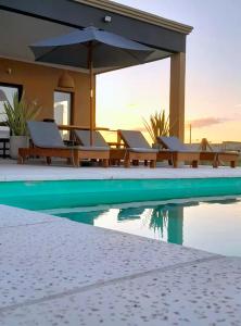 a swimming pool with lounge chairs and an umbrella at Glamping privado con pileta y quincho in San Vicente +35 photos