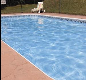 a blue swimming pool with a chair next to it at Quiet Bay Lakeside Escape in Magnetawan