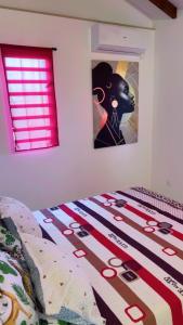 a bedroom with a bed with a picture on the wall at Villa Eden hibiscus in Petit-Canal