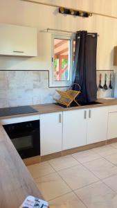 a kitchen with white cabinets and a black appliance at Villa Eden hibiscus in Petit-Canal +9 photos