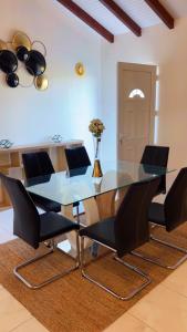 a dining room with a glass table and black chairs at Villa Eden hibiscus in Petit-Canal