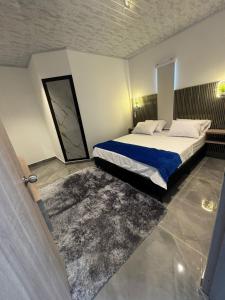 a bedroom with a large bed with a blue blanket at aparta hotel del toro in Puerto Triunfo