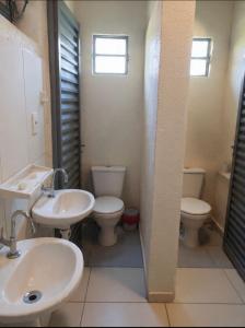 a bathroom with two toilets and a sink and mirror at Chalé Manancial in Socorro