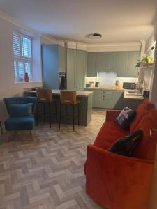 a living room with a red couch and a kitchen at Half Moon Nest - Refurbished throughout for 2026 in Diss +6 photos