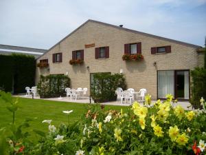 une maison avec des chaises blanches, des tables et des fleurs dans l'établissement Hoevedomein Polderrust, à Nieuport