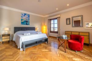 a bedroom with a bed and a red chair at Villa Nobleza, oasis con piscina y gimnasio a 2 min del centro in El Port de la Selva