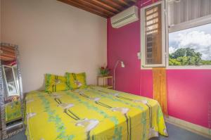 a bedroom with a yellow bed with a window at Villa Les Violettes in Morne-à-lʼEau