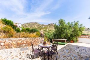 a table and chairs on a patio with a stone wall at Villa for 4 with feature pool & great reviews in Bédar