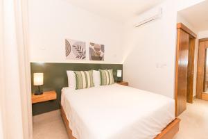 a bedroom with a white bed and a mirror at PF Hotel in San Felipe de Puerto Plata