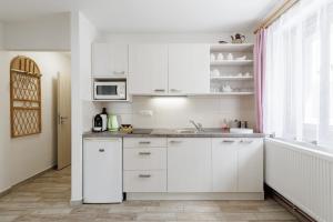a white kitchen with white cabinets and a window at Chalupa U Lávky in Lasenitz