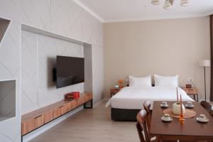 a bedroom with a bed and a tv and a table at Ton Azure Hotel in Tong