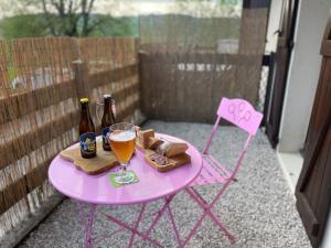 a pink table with a glass of beer and a chair at Au Doubs Village in Métabief