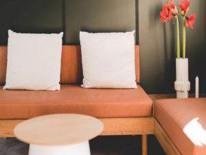 a couch with two pillows and a table with flowers at Wadden lodge comfort in Westerland