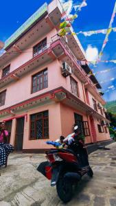 a scooter parked in front of a pink building at Hotel lalu in Rāmechhāp