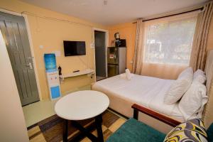 a small room with a bed and a table and a window at Maurine Homestays in Eldoret