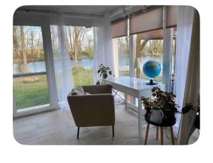 a living room with a table and a chair and windows at Riverside Home Szigetköz in Dunasziget