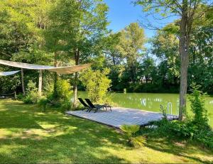 a bench on a wooden boardwalk next to a lake at Riverside Home Szigetköz in Dunasziget