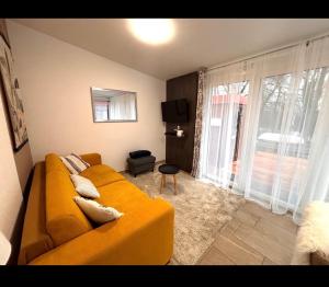a living room with a yellow couch in front of a window at Riverside Home Szigetköz in Dunasziget
