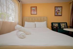 a bedroom with a bed with white sheets and a window at Maurine Homestays in Eldoret