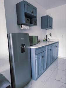 a kitchen with blue cabinets and a stainless steel refrigerator at The Bello Lodging B in Sonsonate