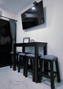 a black table and stools with a television on a wall at The Bello Lodging B in Sonsonate