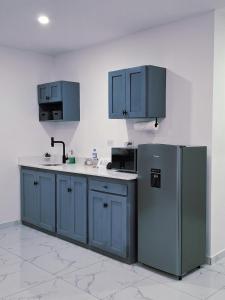 a kitchen with blue cabinets and a refrigerator at The Bello Lodging B in Sonsonate +9 photos