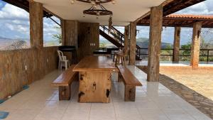 a large wooden table with benches in a pavilion at Recanto do tdias in Mulungu