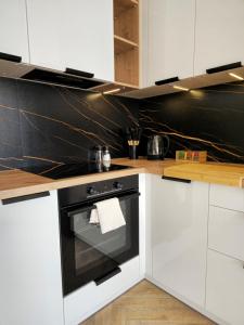 a kitchen with white cabinets and an oven at Borki Lake View Apartment in Radom