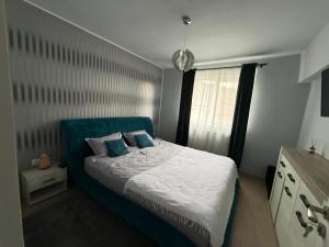 a bedroom with a bed with a blue headboard and a window at Thaleia Retreat in Ocna-Mureşului