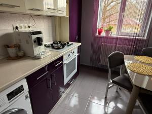 a kitchen with purple walls and a table and a stove at Thaleia Retreat in Ocna-Mureşului