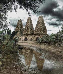 an old stone building with a reflection in the water at Cuanax hotel boutique tematico - Mineral de Pozos in Mineral de Pozos