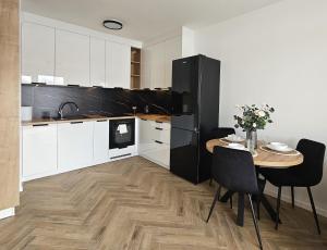 a kitchen with a table and a black refrigerator at Borki Lake View Apartment in Radom
