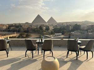 a group of chairs and tables on a roof with pyramids at New City Plaza in Cairo
