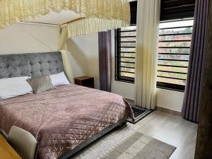 a bedroom with a bed and a large window at Quiet Home Apartment in Kigali