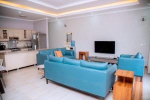 a living room with blue couches and a kitchen at Quiet Home Apartment in Kigali