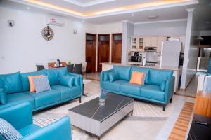 a living room with blue couches and a kitchen at Quiet Home Apartment in Kigali