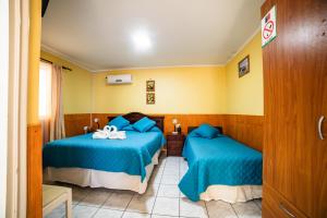 a room with two beds with blue sheets at Hotel Montecarlo in Caldera
