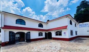 a white building with a red and white facade at Hotel Hacienda Real, Villa in Villa del Carbón