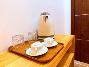 a coffee maker and two hats and glasses on a wooden table at Serenity Stay in Huraa