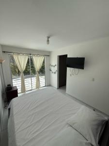 a large white bedroom with a large bed and a window at Cozy house in Dosquebradas in Dosquebradas