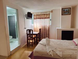 a bedroom with a bed and a table with a chair at Hotel Hacienda Real, Villa in Villa del Carbón