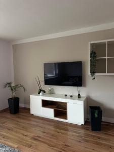 a white entertainment center with a television on a wall at Bright & Spacious 1BR Apartment in Bielefeld