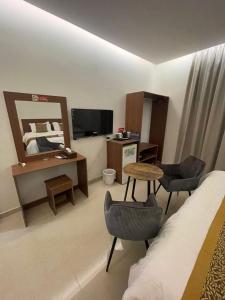 a hotel room with a bed and a desk and a table at شقير للغرف الفندقية 1 in Medina