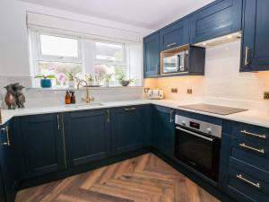 a kitchen with navy blue cabinets and wooden floors at 7 Brewery Pool in Newton Stewart +18 photos